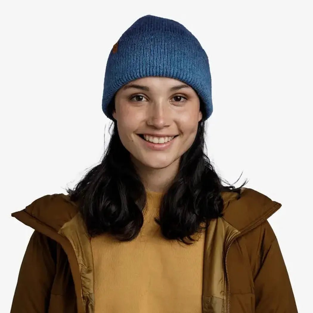 A front view of the Demin Buff Knitted Beanie - Marin on a model wearing a brown jacket against a white background.