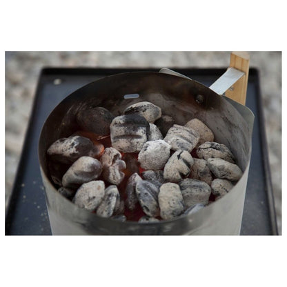 A Camp Chef Charcoal Lighter Basket filled with charcoal sits on a black tray outdoors.