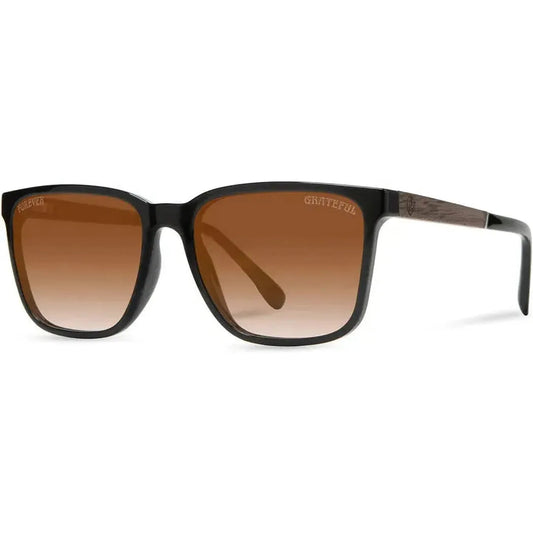 Side view of the Camp Eyewear Crag: Grateful Dead Stealie Edition sunglasses with brown gradient lenses and a black frame against a white background.
