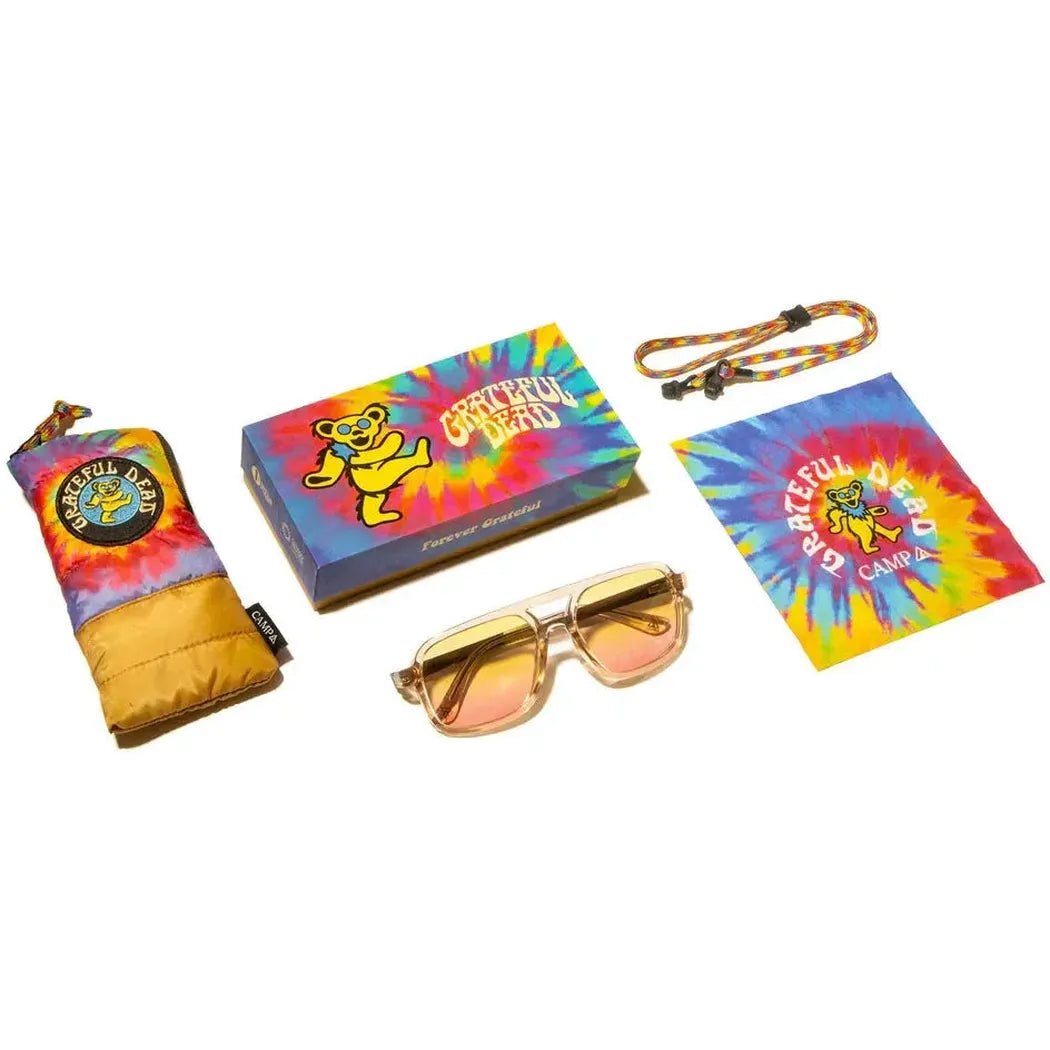 A photo of the Camp Eyewear Glacier: Grateful Dead Bears Edition sunglasses with a tie-dye case and matching accessories laid out on a white background.
