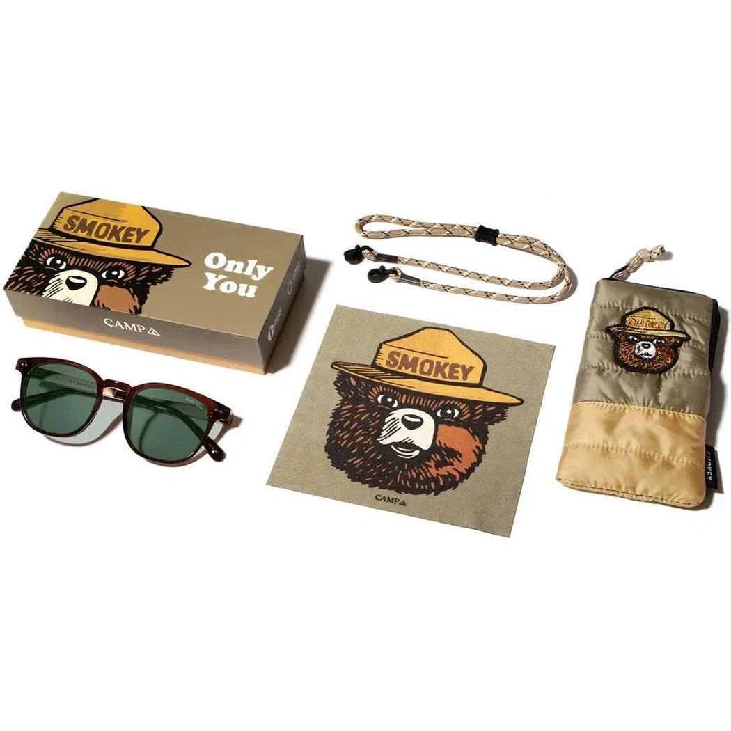 A top-down view of the Camp Eyewear Topo - Smokey Bear sunglasses in Clay, showing the green lenses and brown frames against a white background.