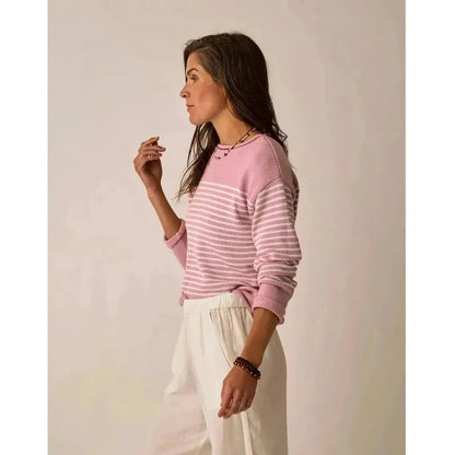 Side view of the Carve Designs Women's Rue Sweater in Light Dusk Stripe on a model wearing white pants against a plain background.