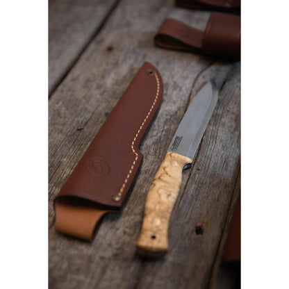 A side view of the Casstrom No 14 Swedish Forest Knife Curly Birch with Firesteel on a weathered wooden surface.