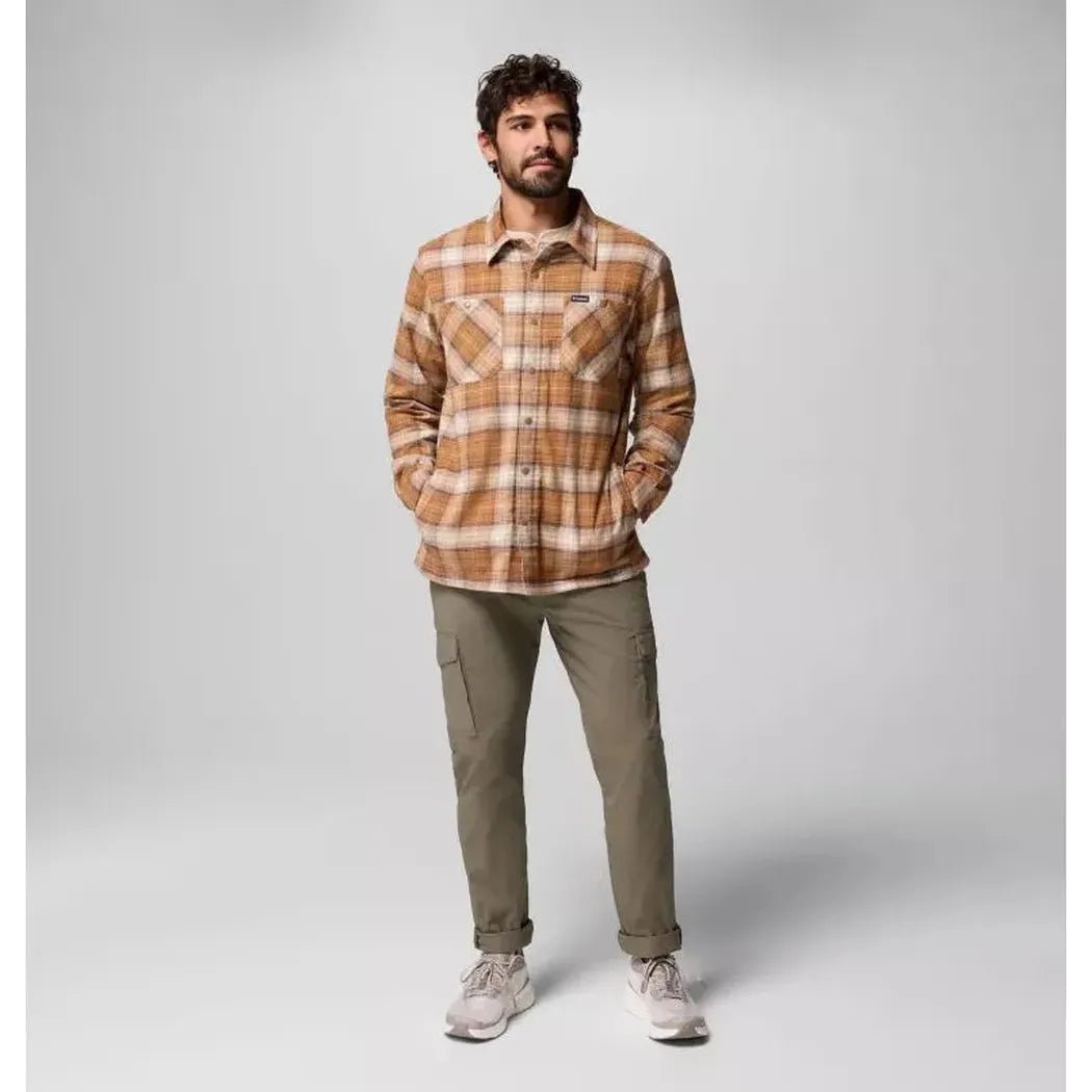 A model wearing the Columbia Sportswear Men's Cornell Woods Fleece Lined Shirt Jacket in Delta Lumberjack Tartan stands against a light gray background.