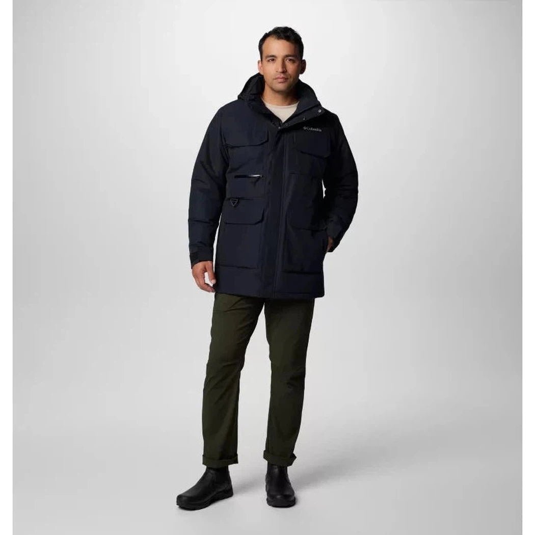 A front view of the Columbia Sportswear Men's Landroamer II Parka in Black on a model wearing olive pants and black boots against a light gray background.