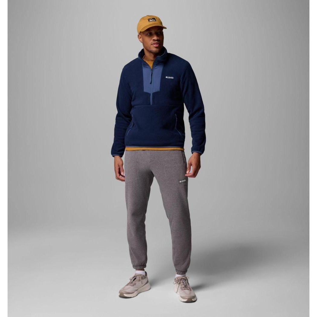 A model wearing the Columbia Sportswear Men's Sequoia Grove Half Zip Fleece in Collegiate Navy/Dark Mountain stands against a gray background.