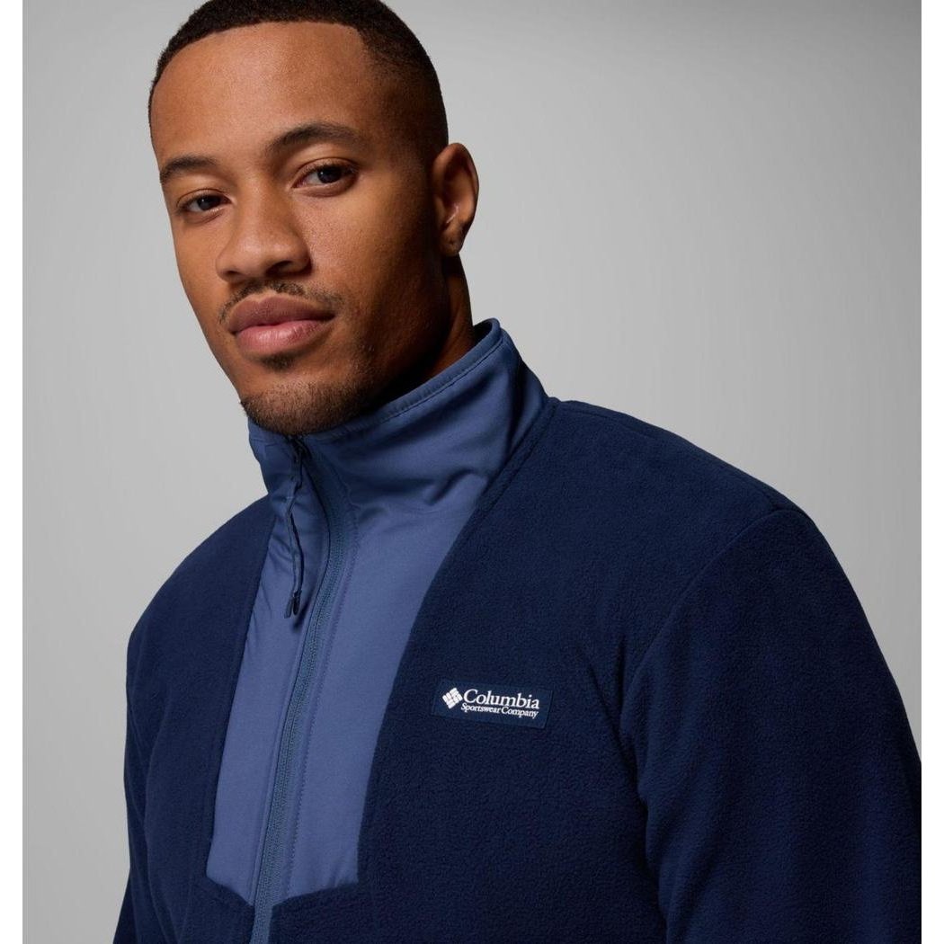 A man wearing a Collegiate Navy/Dark Mountain Columbia Sportswear Men's Sequoia Grove Half Zip Fleece jacket stands against a light gray background.