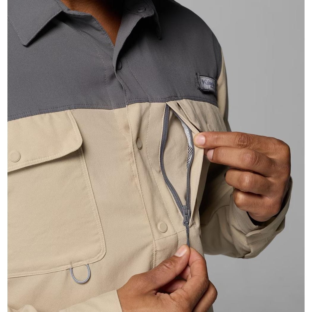 A man shows the zipper on the Columbia Sportswear Men's Shoaltech LS Shirt in Ancient Fossil against a gray background.
