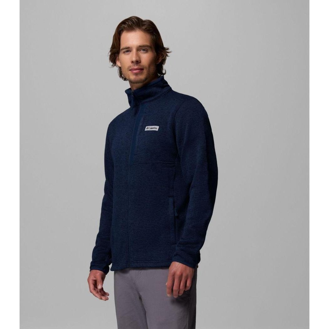 A man wearing the Columbia Sportswear Men's Sweater Weather Full Zip Jacket in Collegiate Navy Heather stands against a plain gray background.