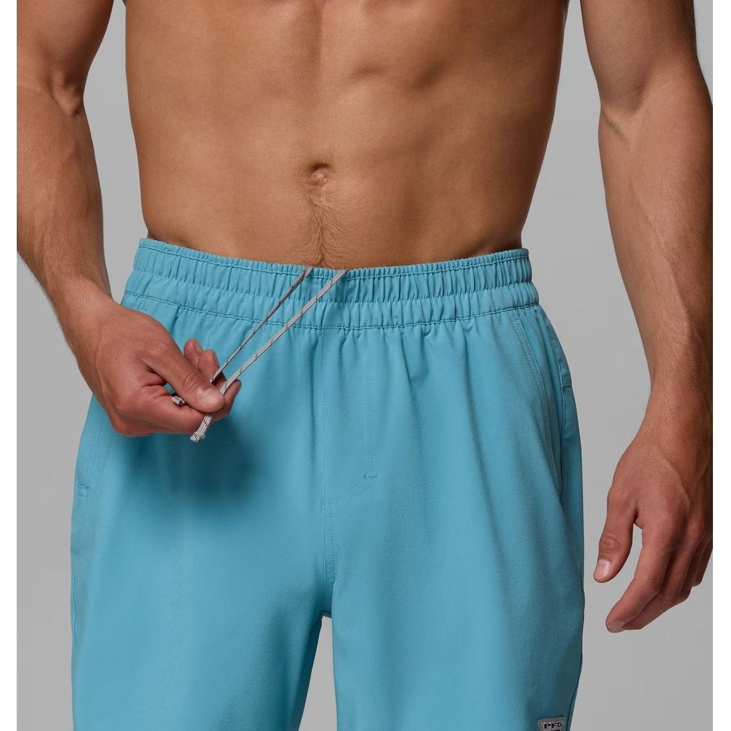 A man wearing the Columbia Sportswear Men's Terminal Roamer Stretch Short in Vintage Blue shows the drawstring and elastic waistband against a plain background.