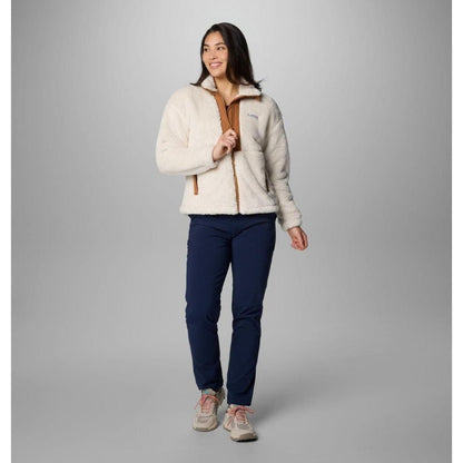 A woman wearing the Columbia Sportswear Women's Boundless Discovery Sherpa Full Zip II Jacket in Chalk/Camel Brown stands against a gray background.