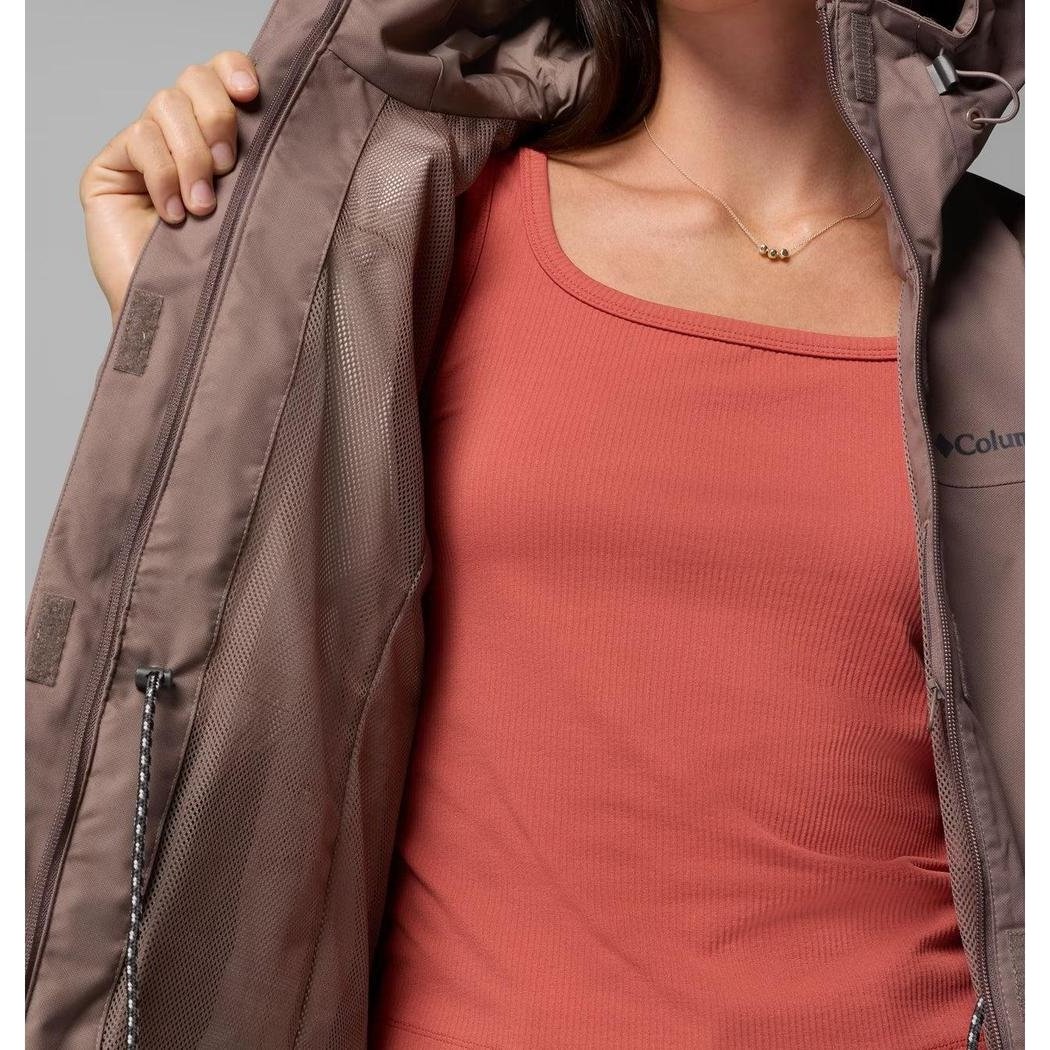 A woman wears the Columbia Sportswear Women's Hikebound II Long Jacket in Iron, showing the interior and a zipper pull.