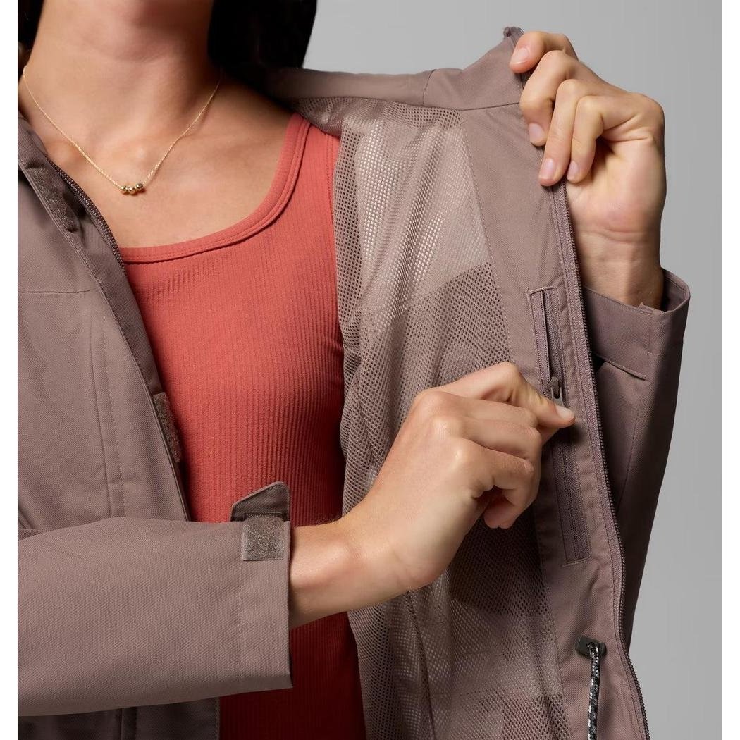 A woman models the Columbia Sportswear Women's Hikebound II Long Jacket in Iron, showing the mesh lining and zipper pocket from a side angle.