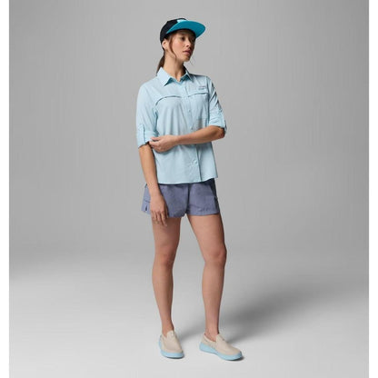 A woman wearing the Columbia Sportswear Women's PFG Castback Woven Long Sleeve in Marine Light stands against a gray background.