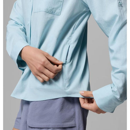 A woman models the Columbia Sportswear Women's PFG Castback Woven Long Sleeve in Marine Light, showing the side zipper and pocket.