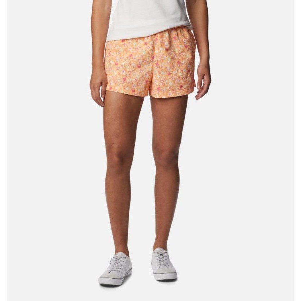 A front view of the Columbia Sportswear Women's Sandy River II Printed Short in Peach, Mini Hibiscus on a model wearing white sneakers against a white background.