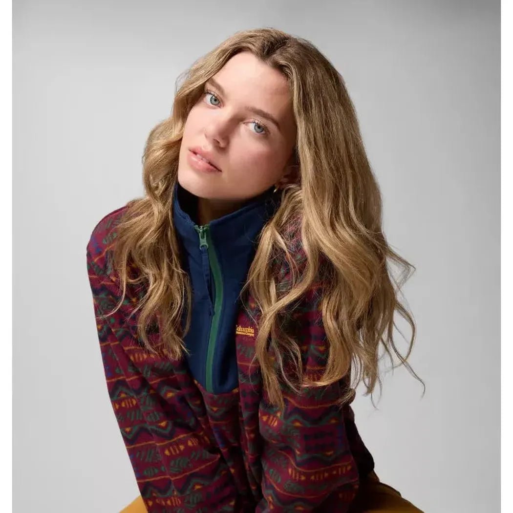 A woman wearing the Columbia Sportswear Women's Sequoia Grove Printed Half Zip in Rich Wine Horizons poses at an angle against a light gray background.