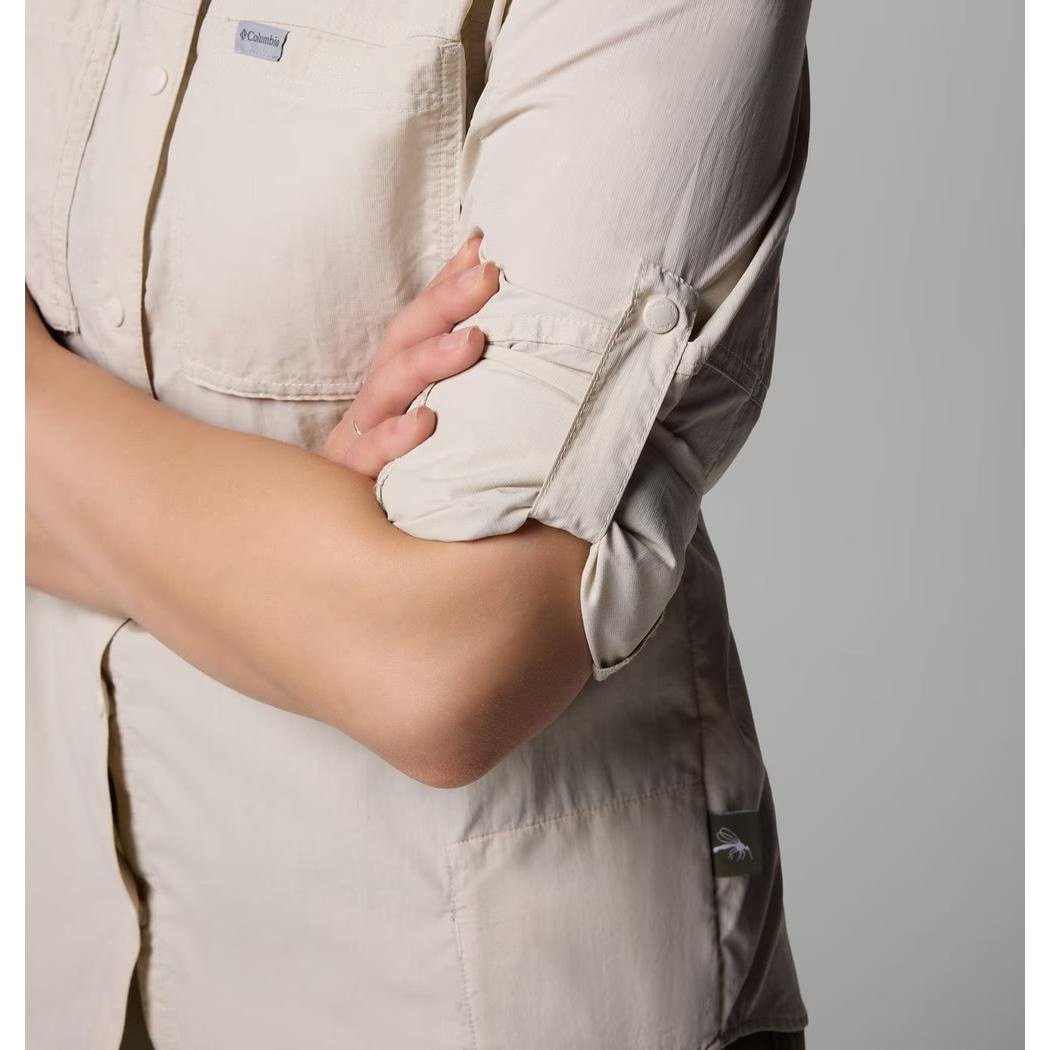 A woman wearing the Columbia Sportswear Women's Skien Valley Long Sleeve Shirt in Dark Stone stands with her arms crossed against a plain background.