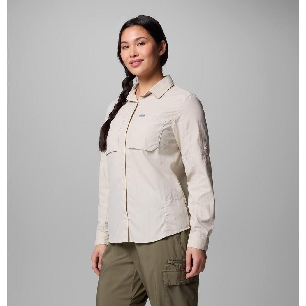 A woman wearing the Columbia Sportswear Women's Skien Valley Long Sleeve Shirt in Dark Stone stands against a plain gray background.