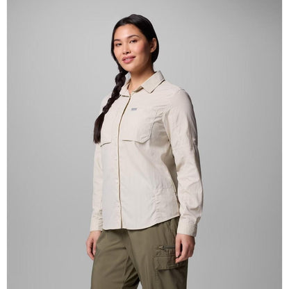 A woman wearing the Columbia Sportswear Women's Skien Valley Long Sleeve Shirt in Dark Stone stands against a plain gray background.