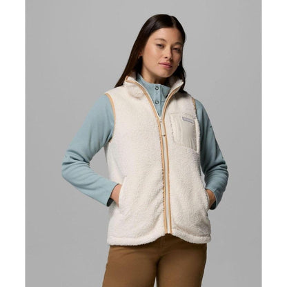 A front view of the Columbia Sportswear Women's West Bend Fleece Vest II in Chalk, showing the model wearing it with a light blue shirt and brown pants against a gray background.