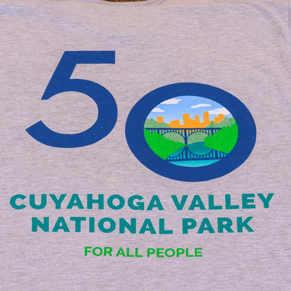 A heather grey unisex t - shirt with the Conservancy for CVNP CVNP 50th Anniversary Logo, showing the 50 and a circular logo with a bridge and cityscape.