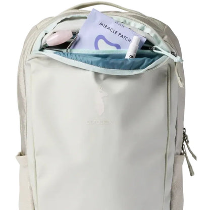 The Mineral Cotopaxi Allpa 18L Daypack shown from the front with its top pocket open, displaying a Miracle Patch and lip balm inside.