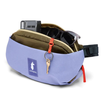 A light blue Cotopaxi Coso 2L Hip Pack with a keychain and sunglasses visible in the open top pocket.