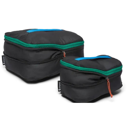 Two black Cotopaxi Cubo Expandable Packing Cube Sets with green zippers and blue top handles sit against a white background.