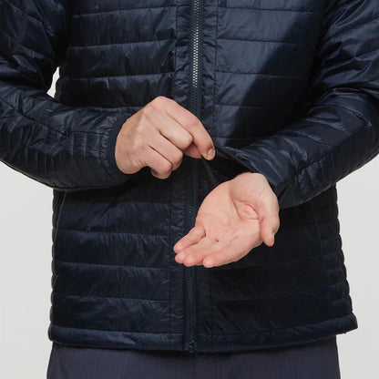 A close-up of the Cotopaxi Men's Capa Insulated Hooded jacket in Carbon, showing the front zipper and a model adjusting the sleeve cuff against a plain background.