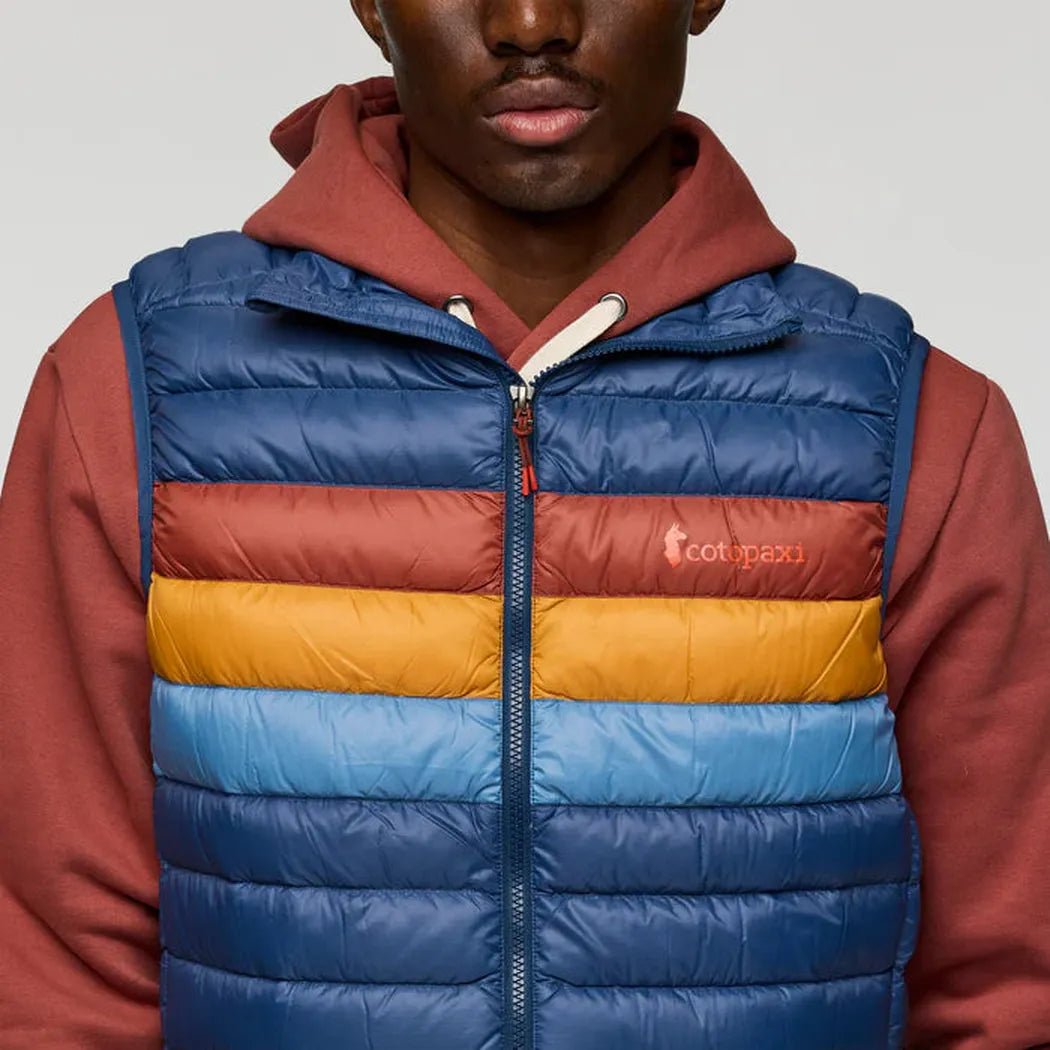 A front view of the Cotopaxi Men's Fuego Down Vest in DeepSeaStripes with a red hoodie underneath against a plain background.