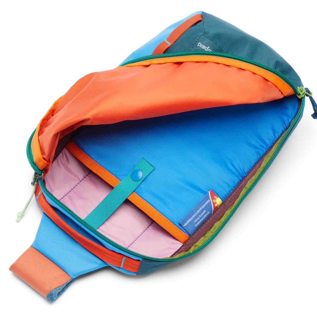 The Cotopaxi Todo 8L Sling in Del Dia color is shown open, displaying its bright blue interior and orange accents against a white background.