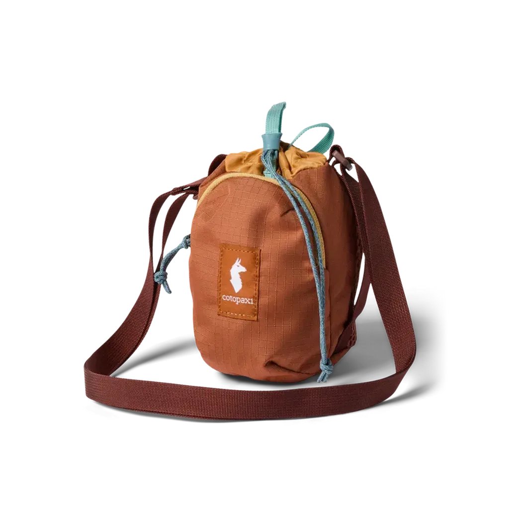 A front view of the Cotopaxi Todo Water Bottle Sling in Honeycomb/Whiskey with a brown shoulder strap and a drawstring closure, set against a white background.