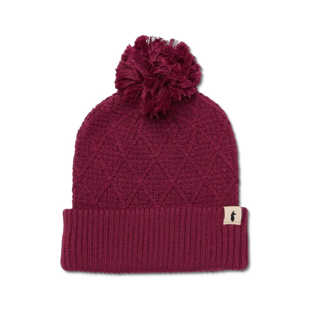 A front view of the Cotopaxi Tozo Beanie in Iceberg color with a pom pom and a small tag on the cuff against a white background.