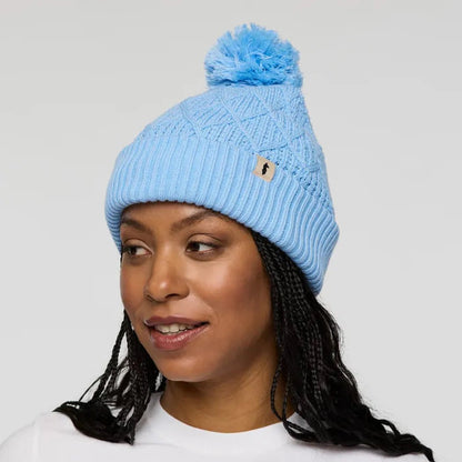 A woman wears the Cotopaxi Tozo Beanie in Iceberg color, shown from the side against a plain white background.