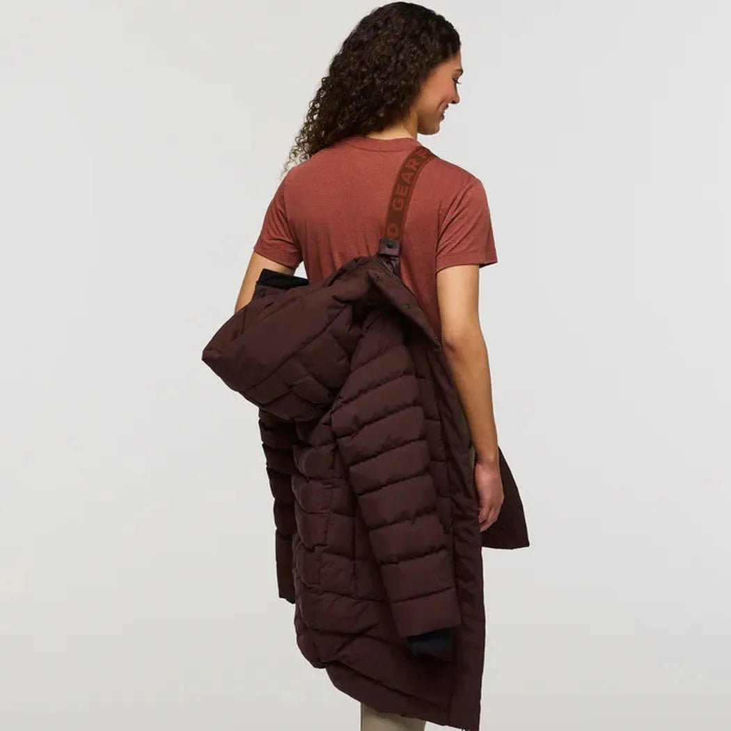 Back view of the Cotopaxi Women's Alivio Down Parka in Coffee, showing the model wearing it with a brown strap bag against a plain white background.