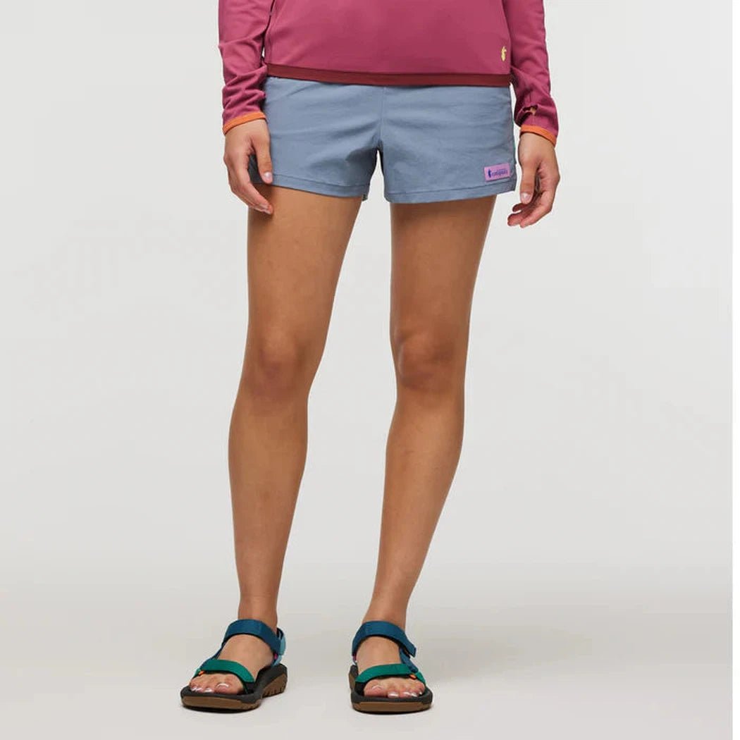 A front view of the Cotopaxi Women's Brinco Short in Tempest on a model wearing blue sandals against a white background.
