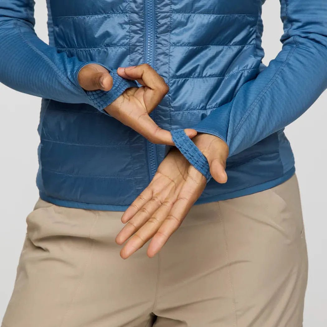 A woman models the Fjord Cotopaxi Women's Capa Hybrid Insulated Jacket, showing the adjustable cuffs against a plain background.