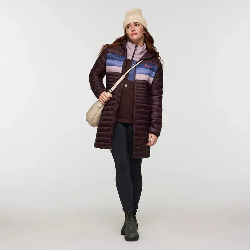 A model wearing the Cotopaxi Women's Fuego Down Parka in Coffee Stripes stands against a plain white background.