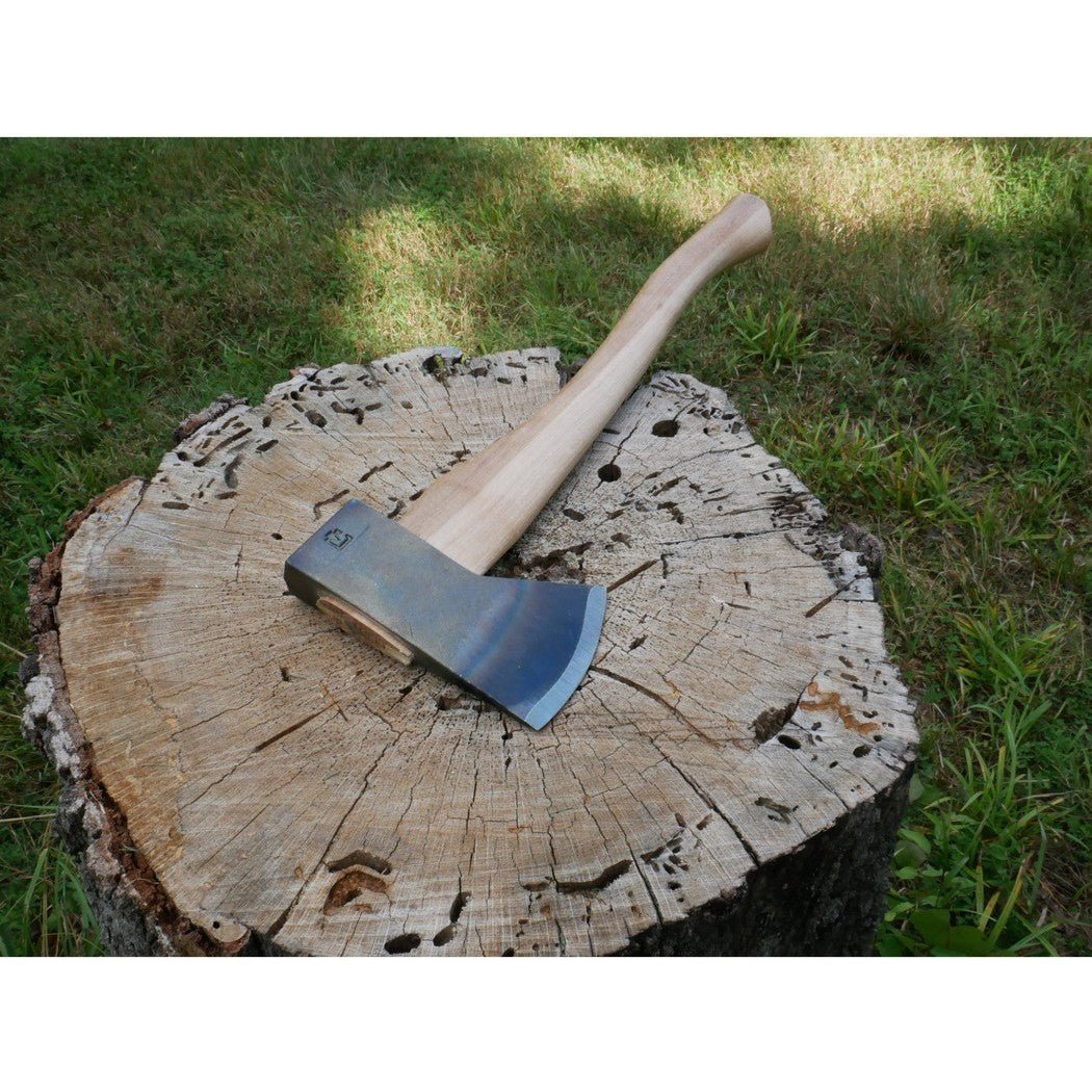 A Council Tool Co. Hudson Bay Camp Axe with 18" handle rests on a tree stump in a grassy outdoor setting.