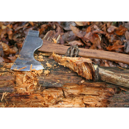 A close-up of the Council Tool Co. Wood-Craft Camp Carver axe on a wood chopping block with wood shavings and leaves in the background.