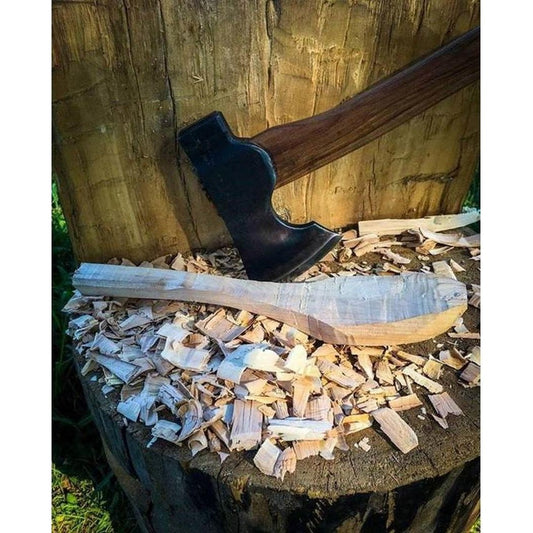 A 22" handle Council Tool Co. Wood Craft Camp Carver axe rests on wood shavings with a hand-carved wooden spoon nearby.