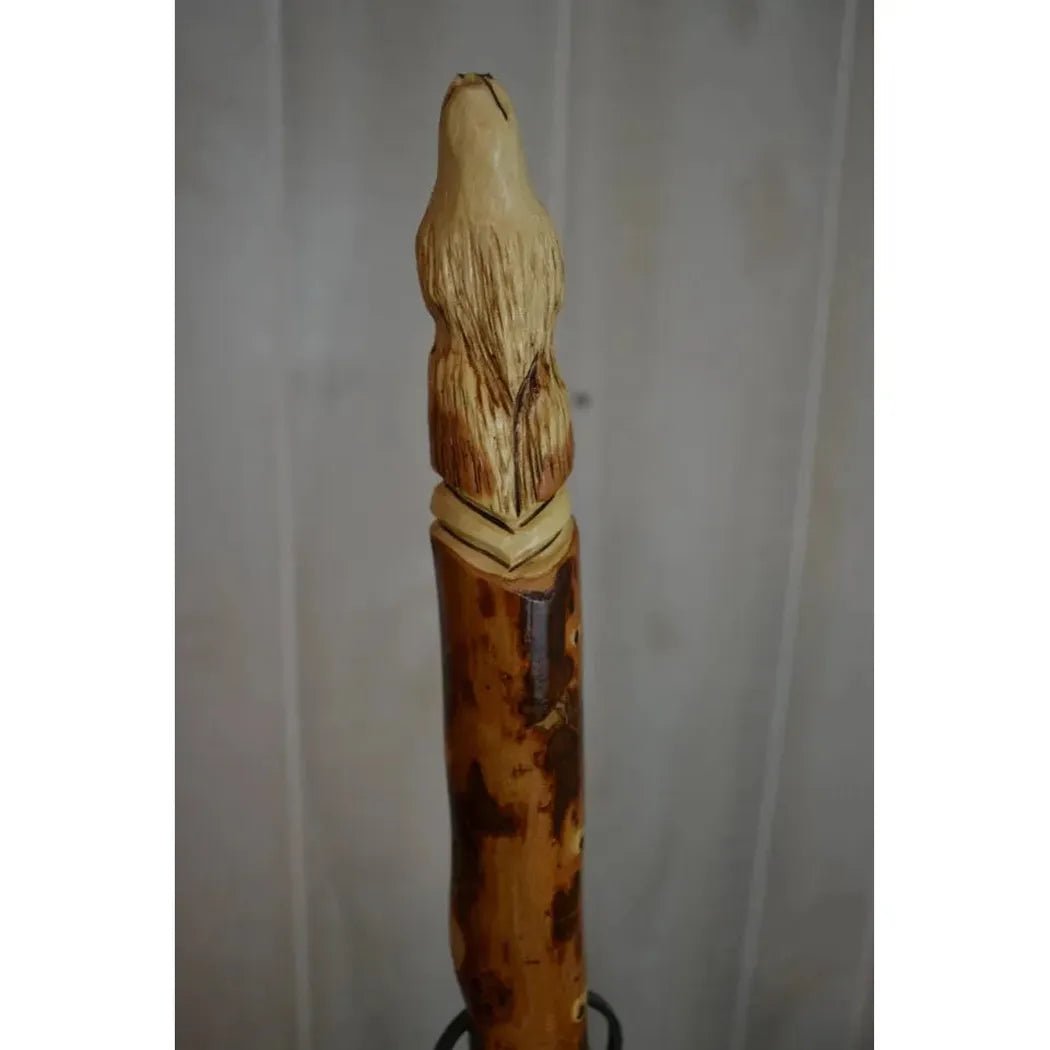 A close-up of the Creation Carvings Walking Stick with Wolf Head Craving showing the detailed wolf head carving and natural wood texture against a plain background.