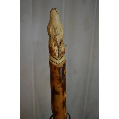 A close-up of the Creation Carvings Walking Stick with Wolf Head Craving showing the detailed wolf head carving and natural wood texture against a plain background.