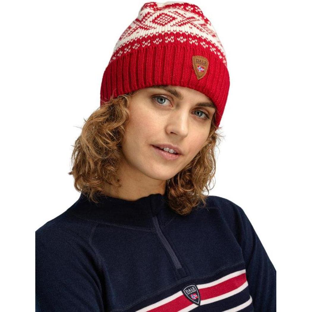 A woman wears the Dale Of Norway Cortina 1956 Hat in Navy White, with a red and white pattern, against a white background.
