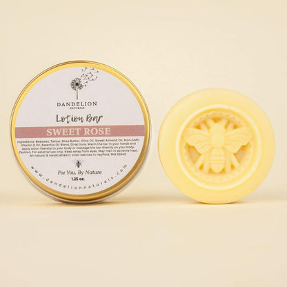 A round tin of Dandelion Naturals Rose Lavender Vanilla Tallow Lotion Bar sits next to a yellow bar with a bee design, both against a light background.