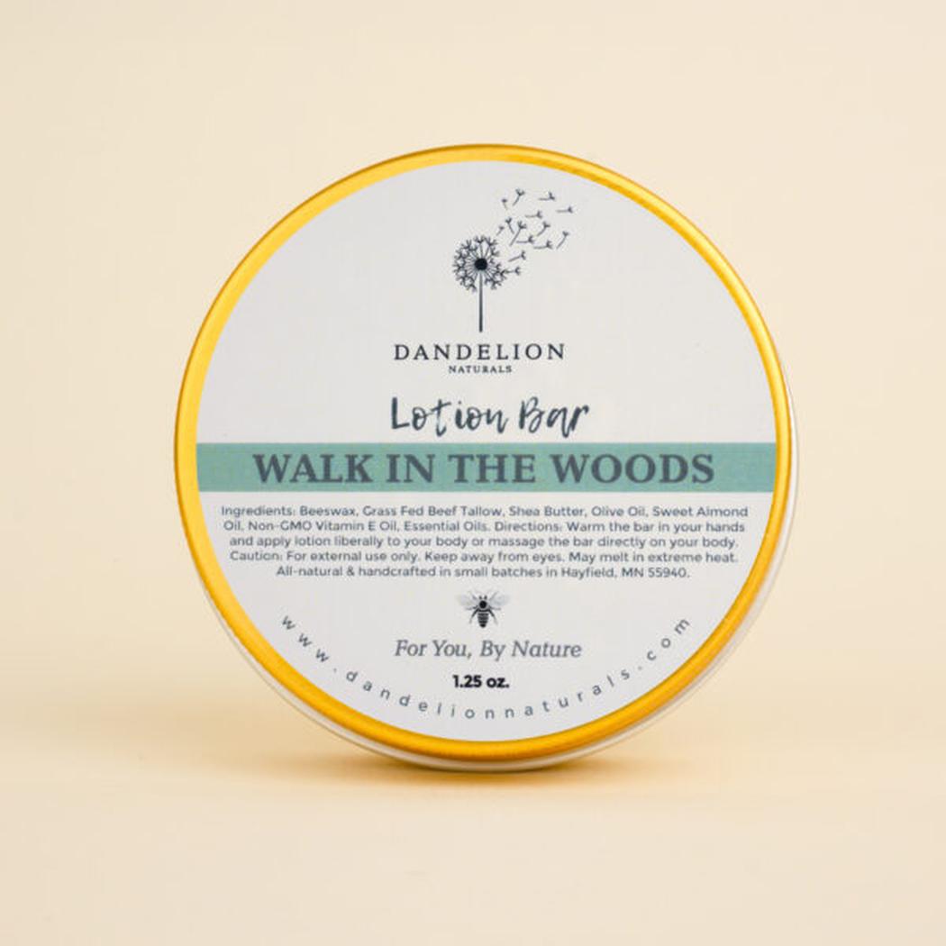 A round Dandelion Naturals Walk In The Woods lotion bar with a yellow rim sits on a light background.