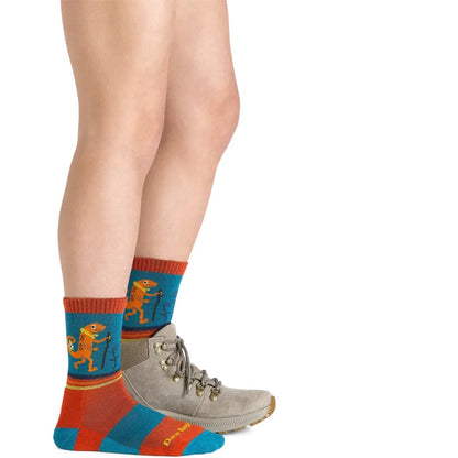 Side view of the Darn Tough Kid's Sal Micro Crew Lightweight With Cushion Lava socks on a child wearing a gray hiking boot against a white background.