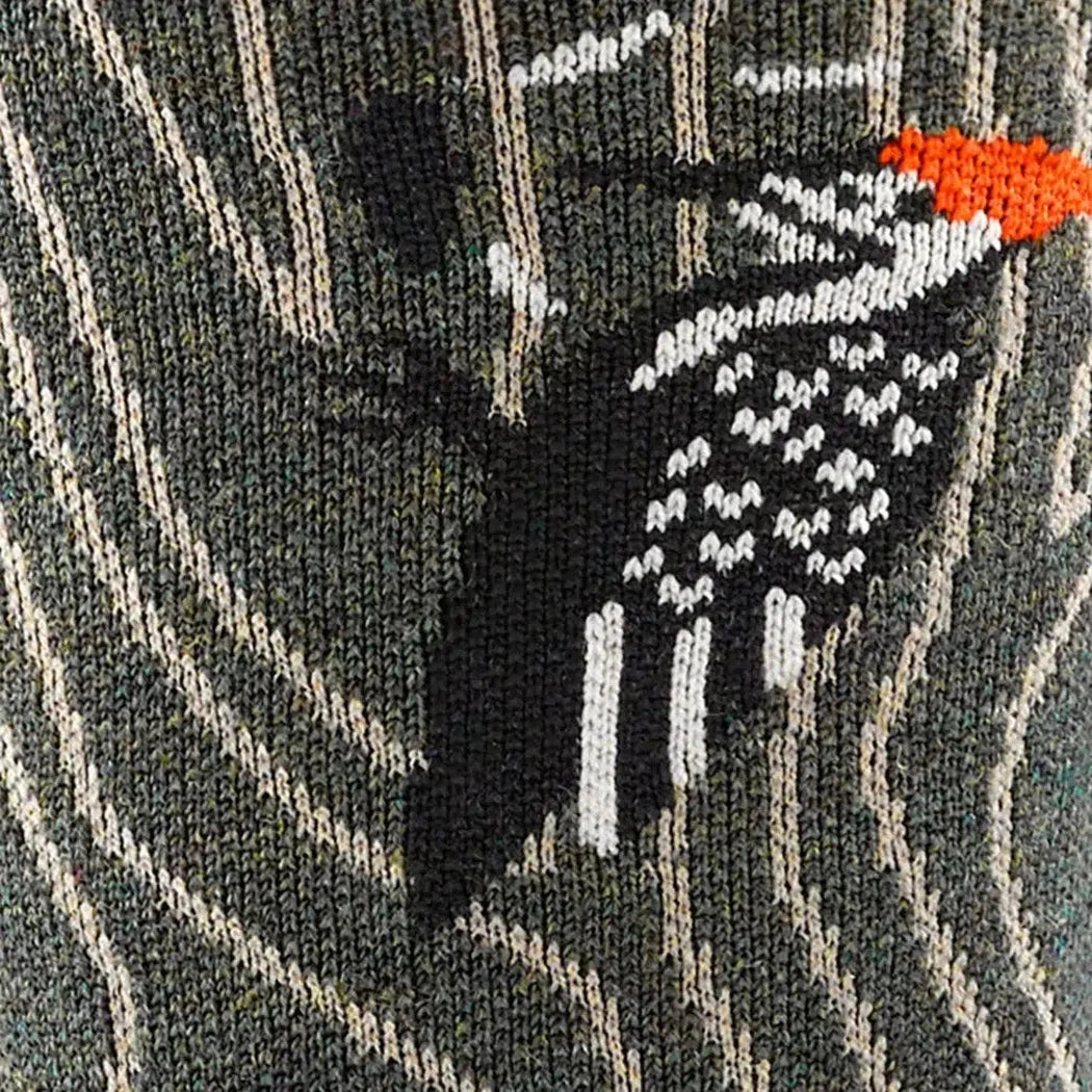 A close-up of the Darn Tough Men's Woody Crew Lightweight socks in Forest color, showing the detailed woodpecker design on the front.