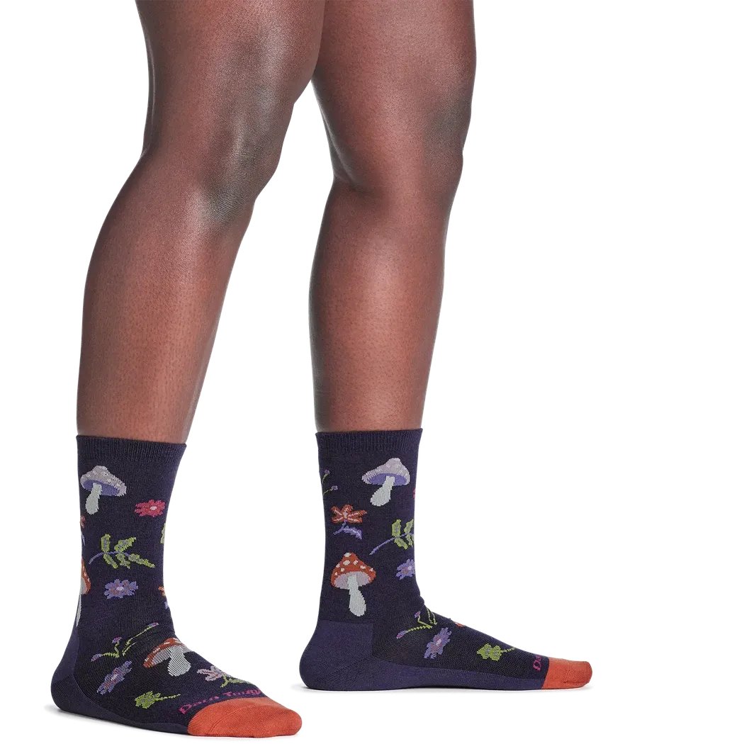 A side view of the Darn Tough Women's Shroom Bloom Crew Lightweight Lifestyle Socks in Blackberry showing the colorful mushroom and floral designs on the dark socks against a white background.